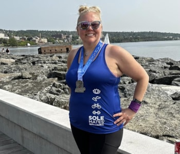 SoleMate smiles with a medal on her neck in front of Lake Superior
